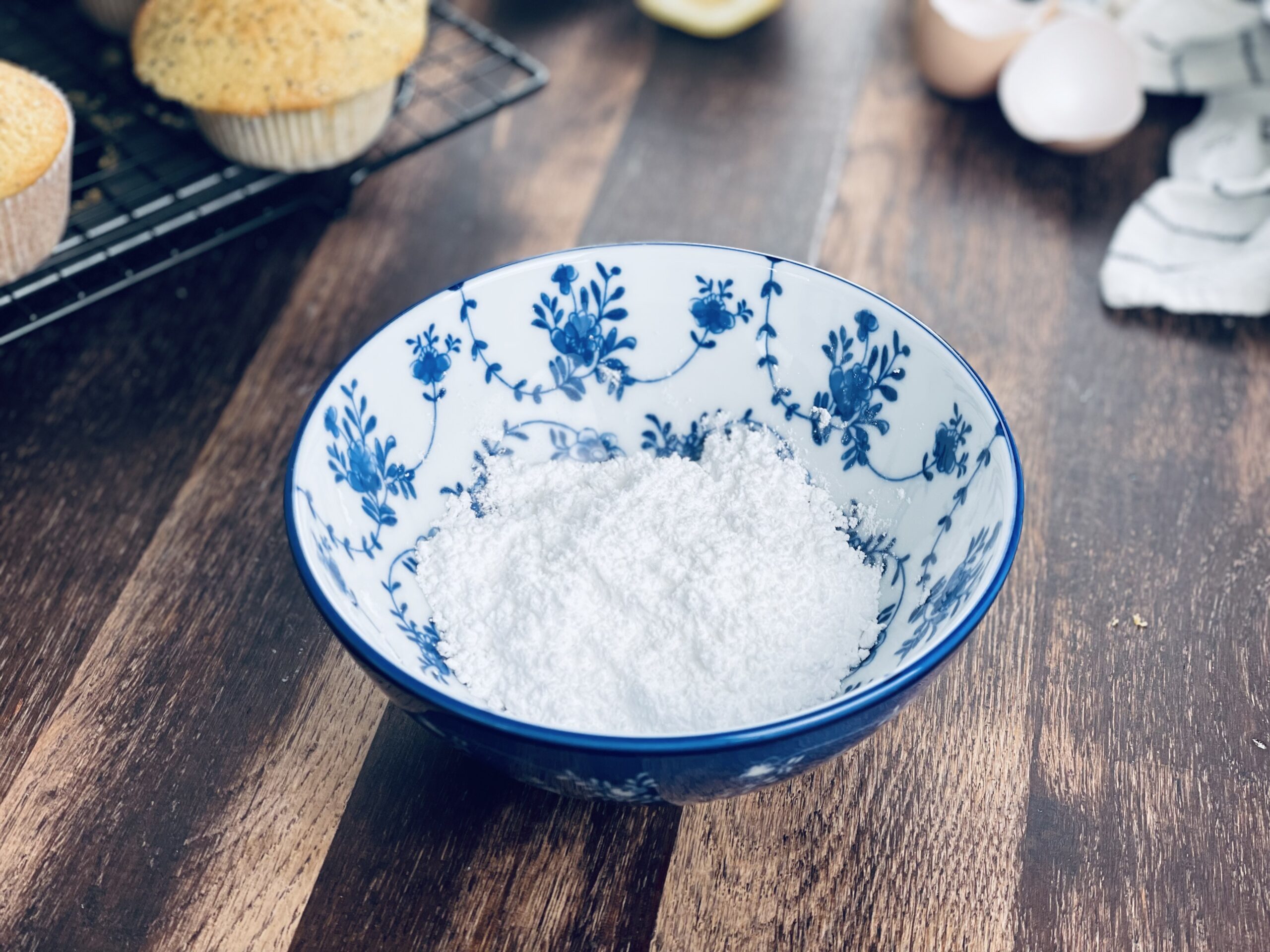 Glasur für Zitronen-Mohn Sauerteig Muffins herstellen. Puderzucker in eine Schale geben 