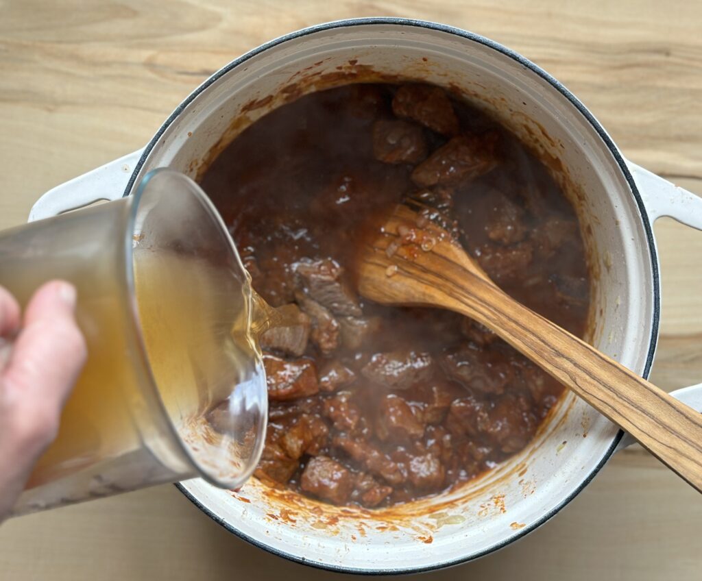 Rinderbrühe in das Rindergulasch geben