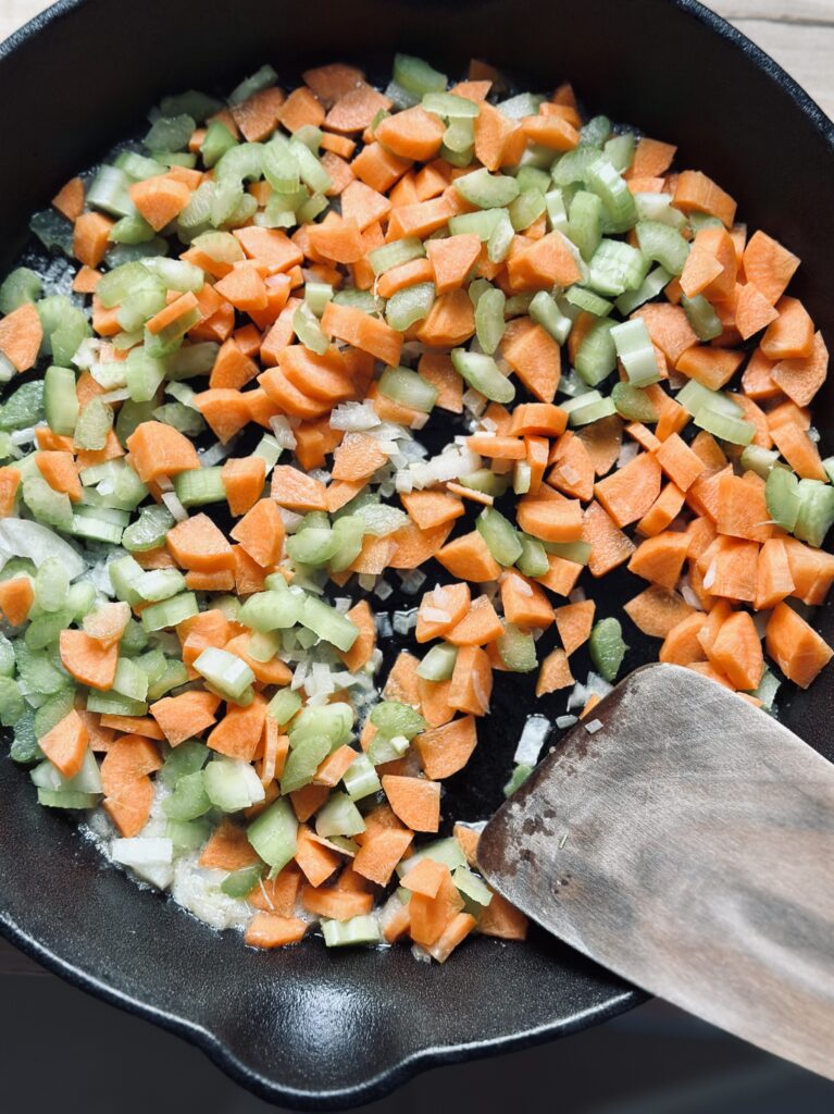 Karotten, Sellerie und Zwiebeln für die Shepherd's Pie Füllung mit Butter dünsten