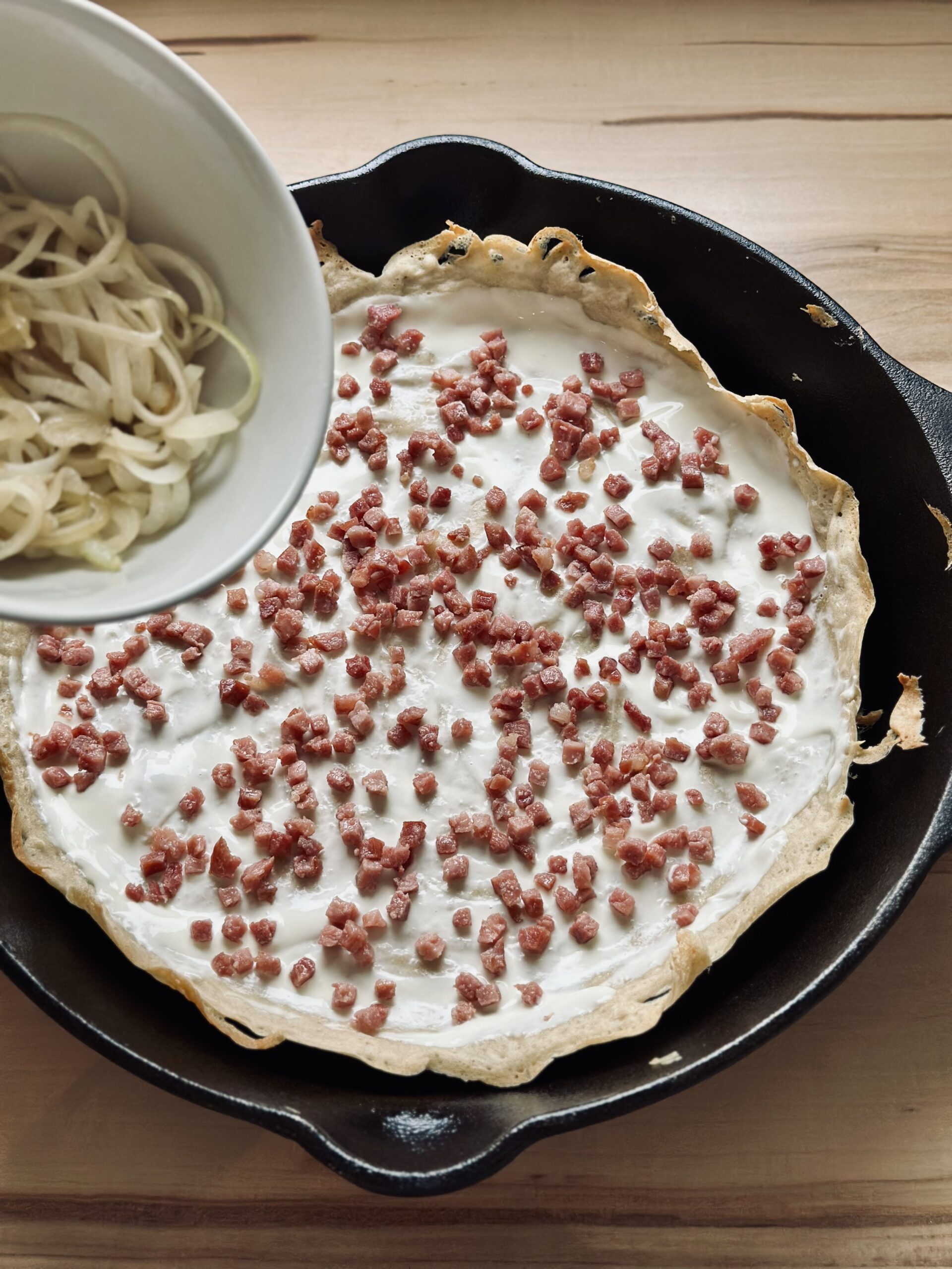 Zwiebelscheiben auf dem Flammkuchen verteilen