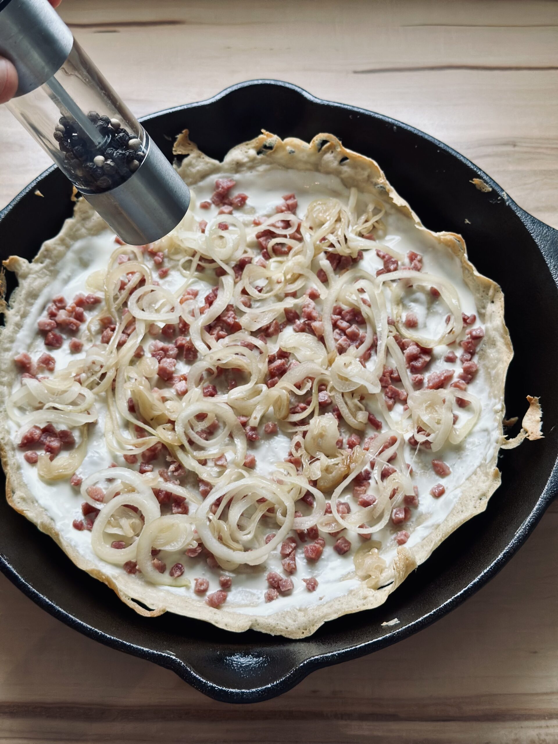 Pfeffer und ggf. Salz über den Flammkuchen geben