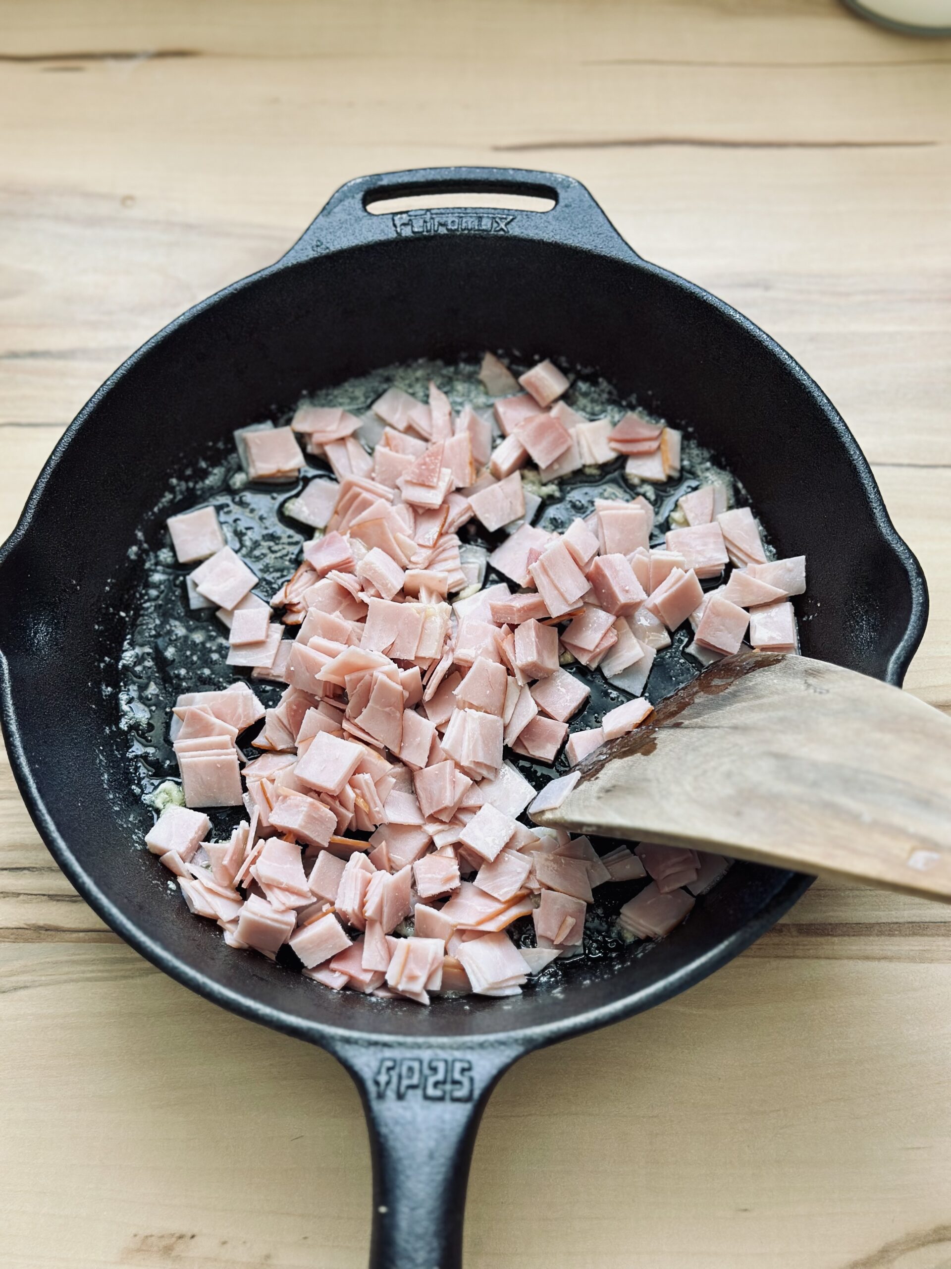 Geschnittenen Schinken zu dem Knoblauch geben und kurz anbraten