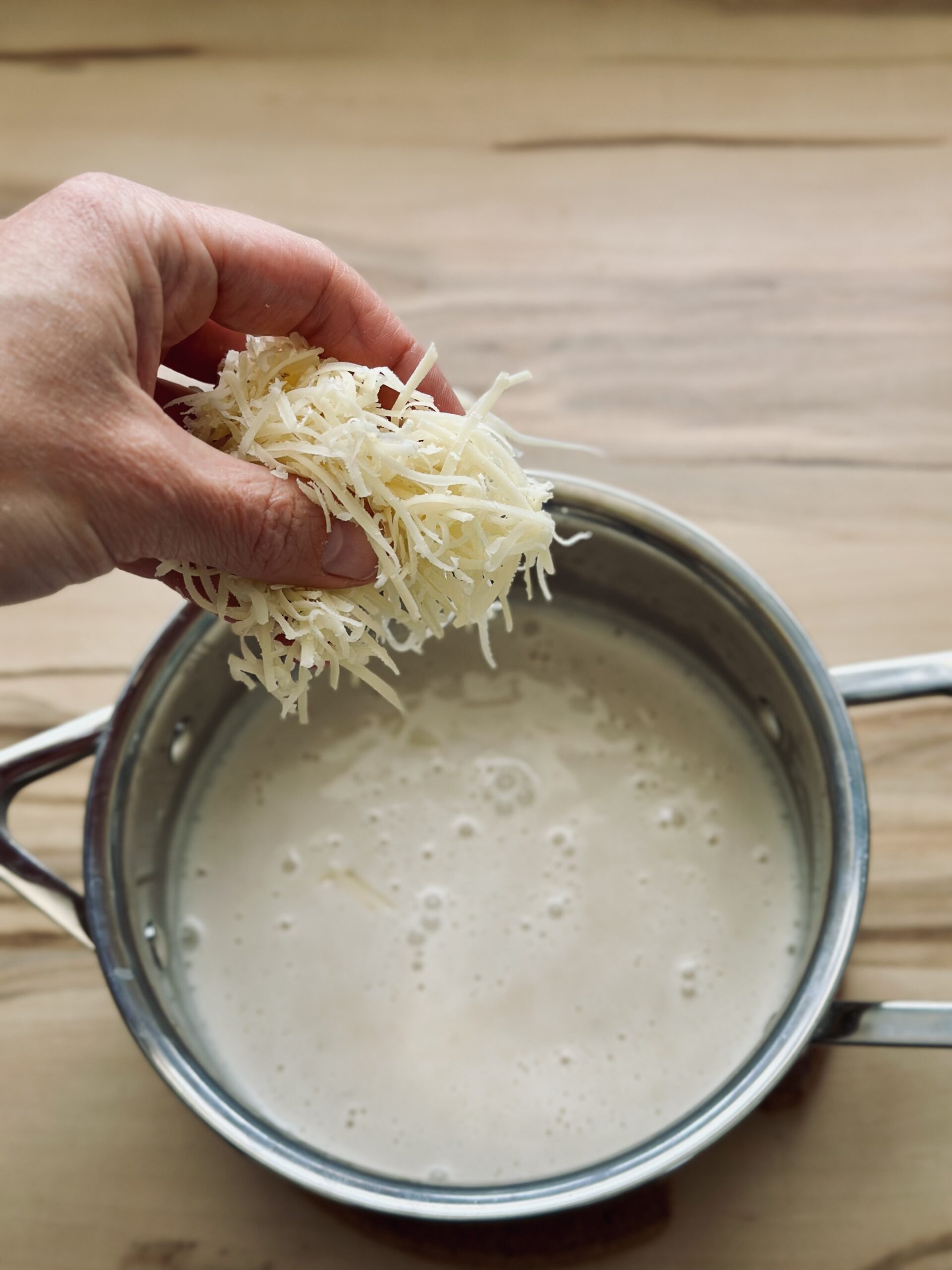 Käse zu der Soße hinzufügen