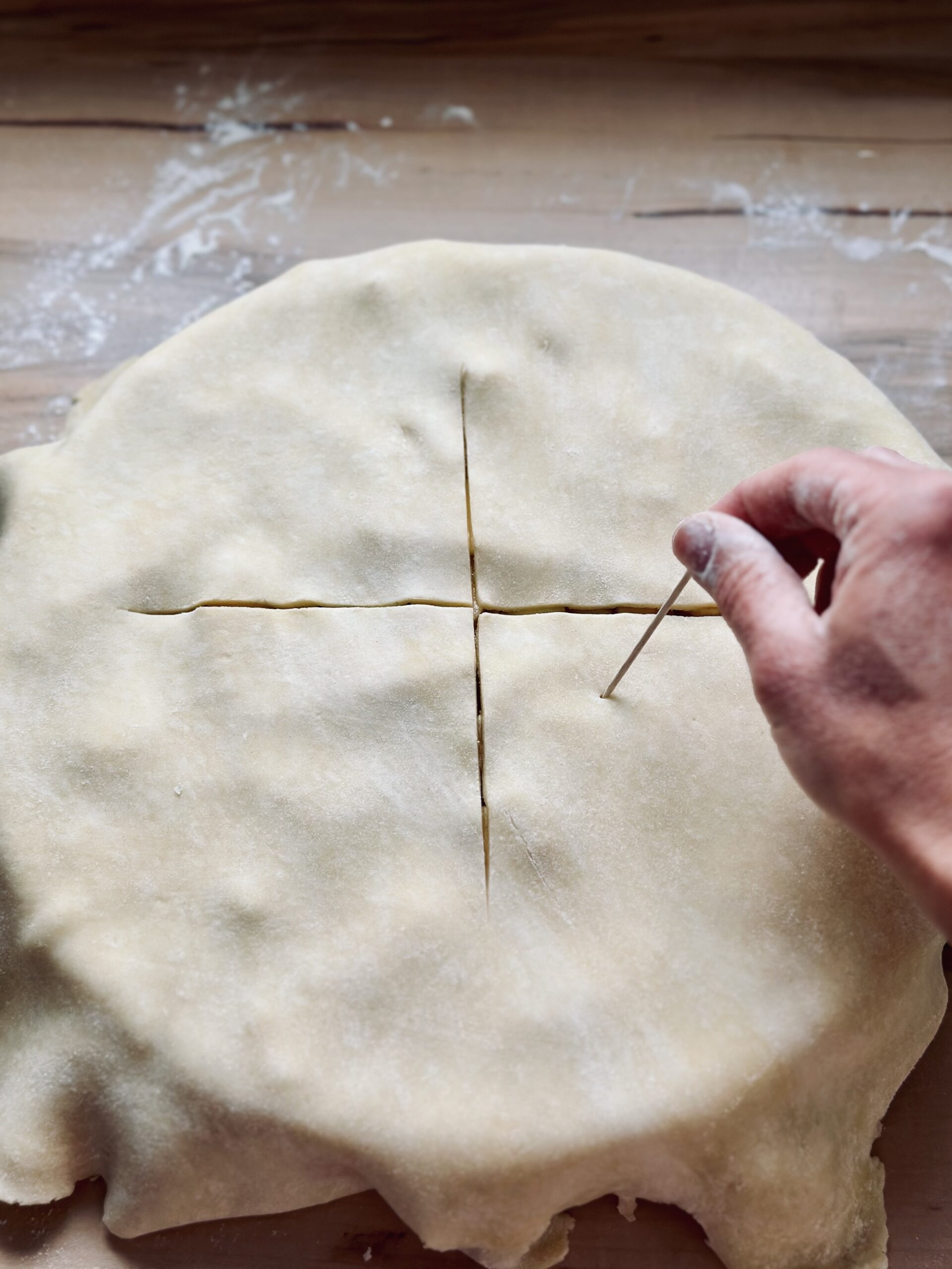 Deckel auf den Kuchen legen und ein Kreuz Einscheiden und ein paar Löcher einstechen