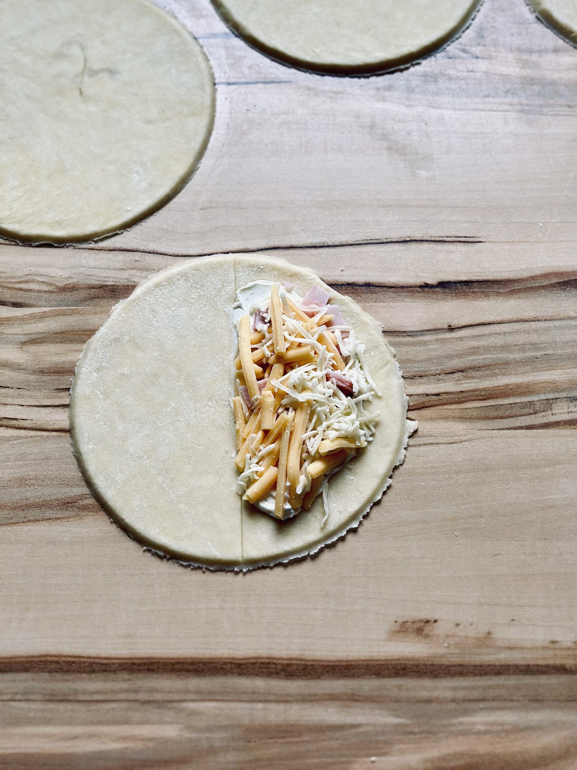 Käse über den Schinken und Frischkäse geben
