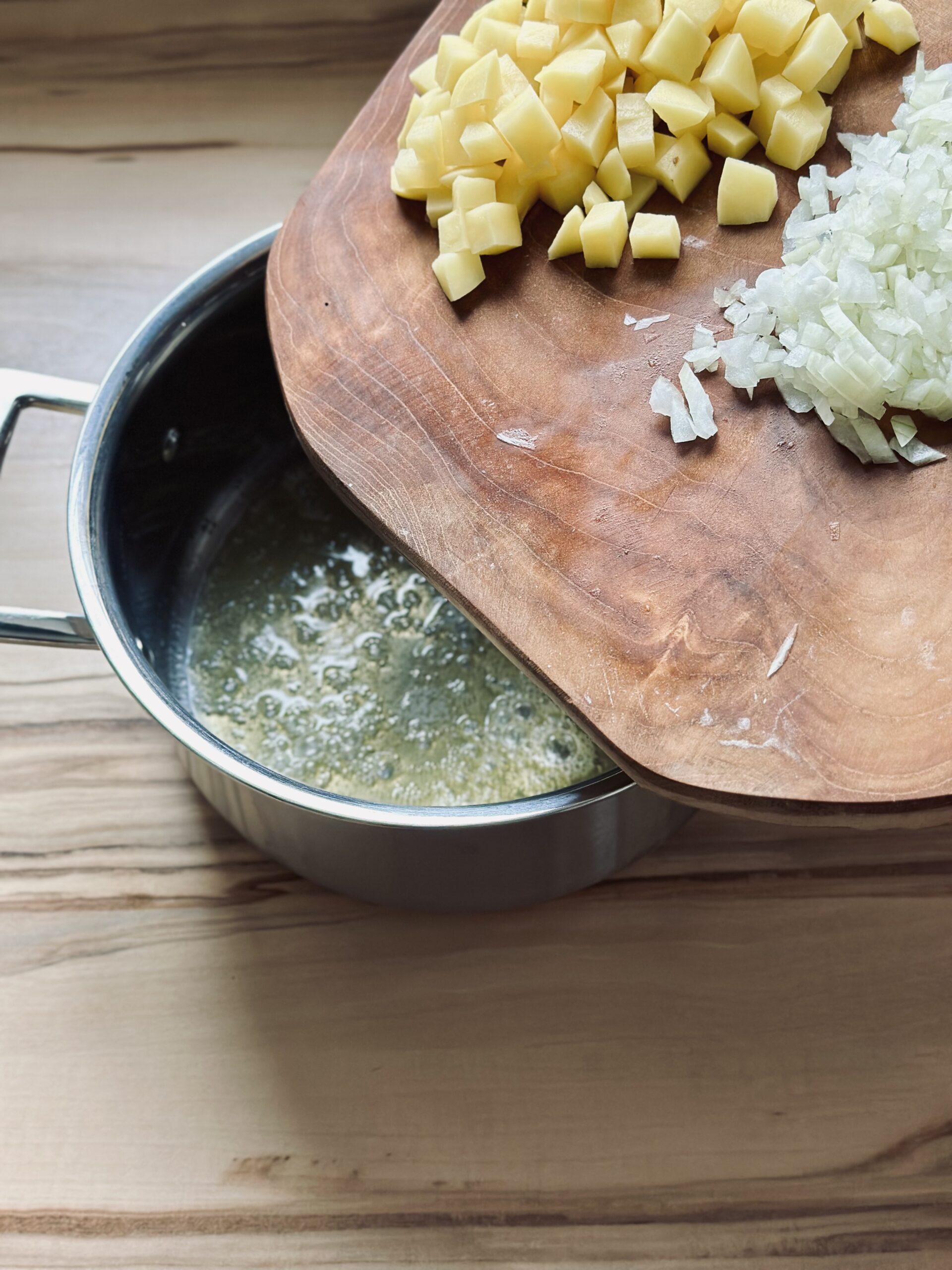 Kartoffeln und Zwiebeln zu der Butter geben