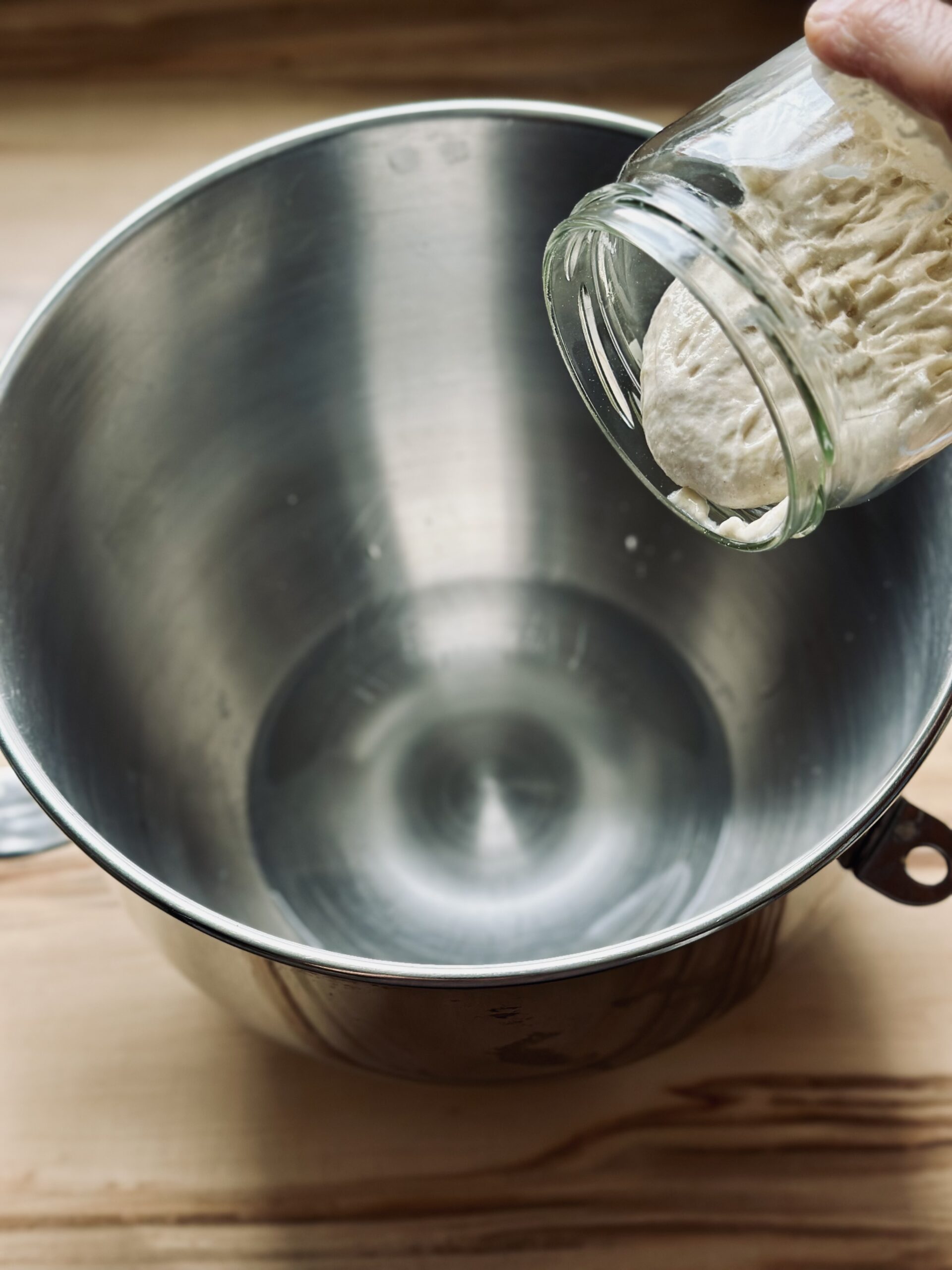 Sauerteig zu dem Wasser in der Rührschüssel geben