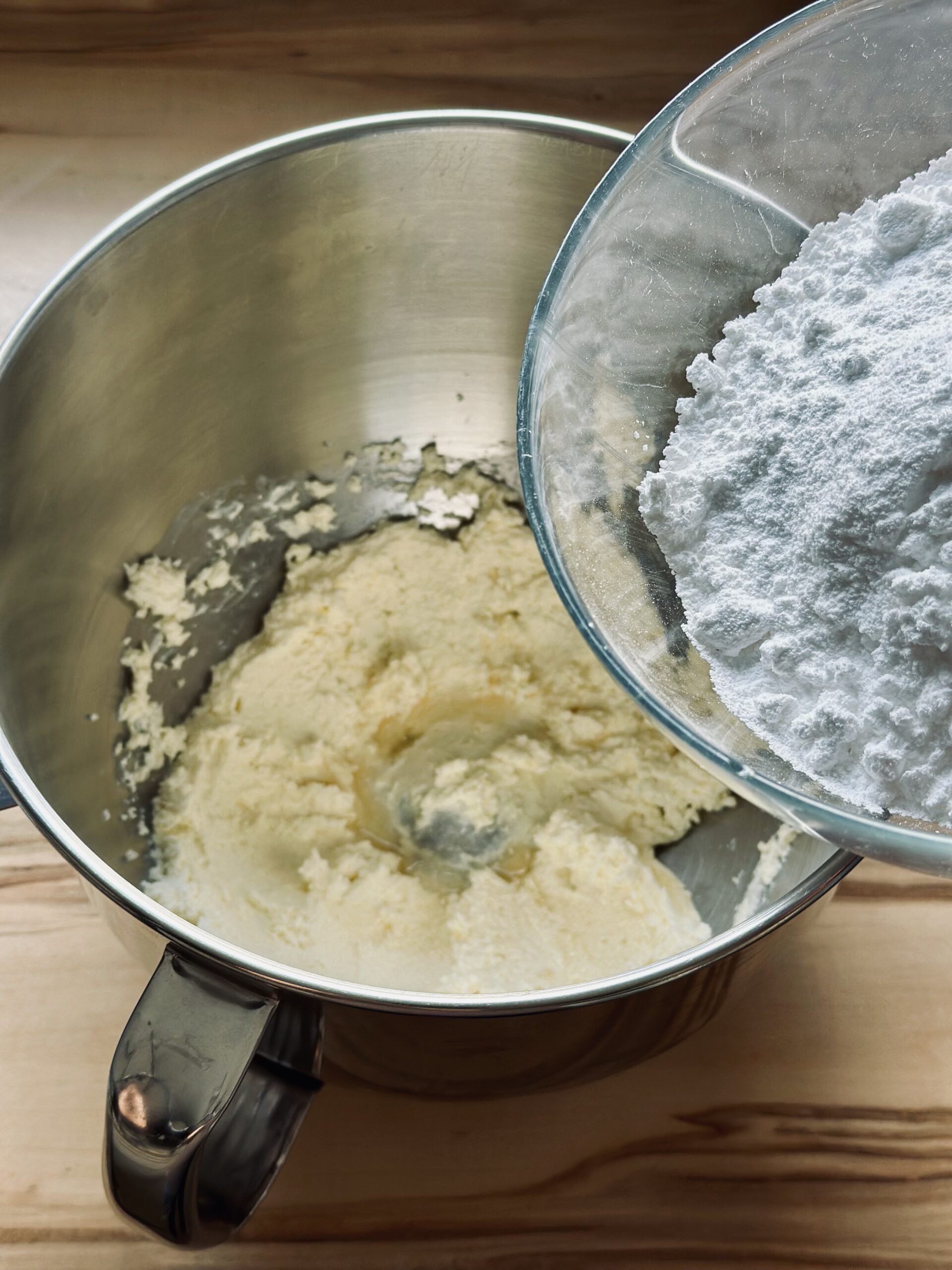 Puderzucker in die Frosting Masse geben und gut verrühren bis der Zucker komplett in der Butter Masse aufgenommen ist.