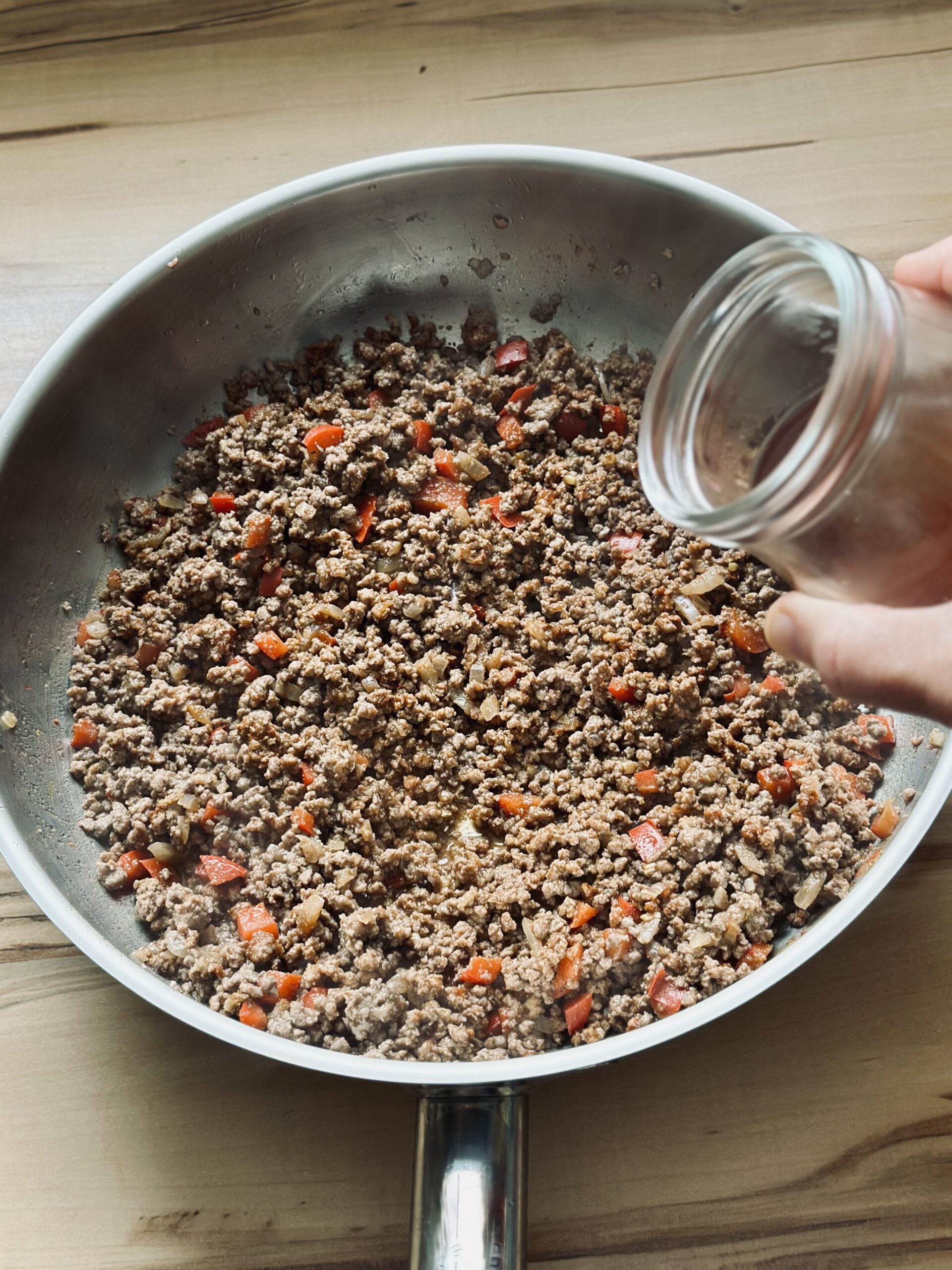 Gemüsebrühe zu dem Fleisch geben und einrühren 
